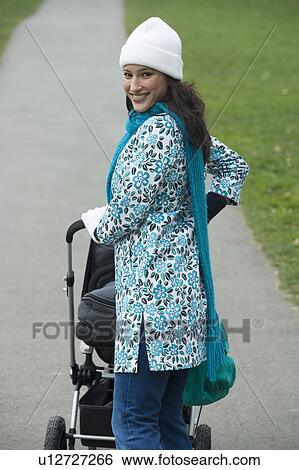 Stock Photograph - Mother pushing stroller in park. Fotosearch