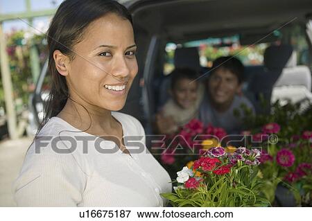 Mother standing by back of minivan holding flowers, portrait View Large Photo Image Stock Photo - Mother standing by back of minivan holding flowers, portrait. Fotosearch
