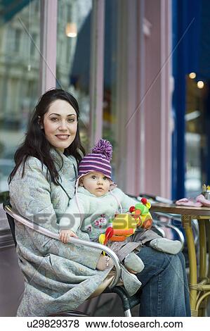 Mother with baby on her laps sitting outside cafe View Large Photo Image Stock Photo - Mother with baby on her laps sitting outside cafe. Fotosearch