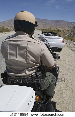 Picture - Motorcycle police officers sits on his vehicle. Fotosearch