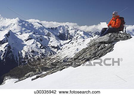Mountain climber using laptop on mountain peak View Large Photo Image Stock Image - Mountain climber using laptop on mountain peak. Fotosearch