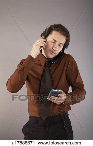 Multi-tasking businessman using mobile phone View Large Photo Image Stock Image - Multi-tasking businessman using mobile phone. Fotosearch
