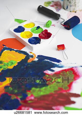 Stock Image - Paints and painting rollers lying next to painting, elevated view. Fotosearch