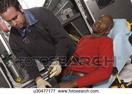 Paramedic helping man in ambulance View Large Photo Image Stock Photo - Paramedic helping man in ambulance. Fotosearch
