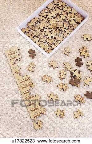 Stock Image - Partly assembled jigsaw puzzle with extra pieces in box, elevated view. Fotosearch
