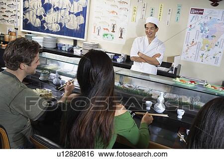Stock Photograph - People eating at sushi bar. Fotosearch