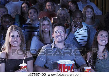 Stock Image - People holding soda and popcorn, Watching Movie in Theatre. Fotosearch