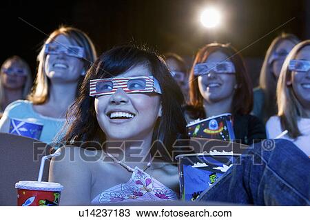Stock Image - People wearing 3-d glasses watching 3-D movie in theatre. Fotosearch