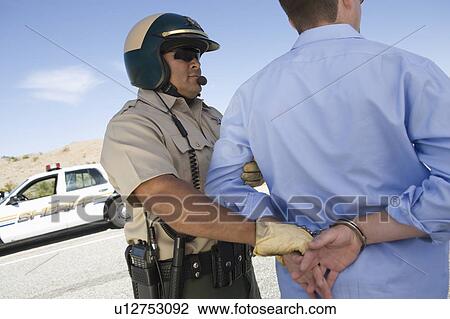 Stock Image - Police office apprehends male driver. Fotosearch