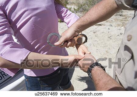 Stock Photo - Police officer arresting female driver. Fotosearch