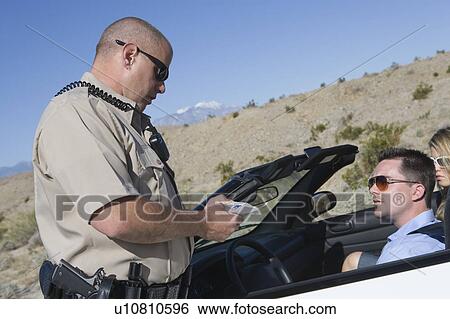 Stock Photograph - Police officer checking on driver in desert. Fotosearch
