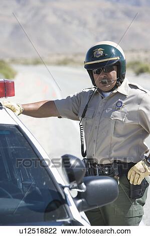Stock Image - Police officer stands with his vehicle. Fotosearch