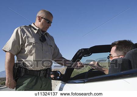 Stock Photo - Policeman giving driver speeding ticket. Fotosearch
