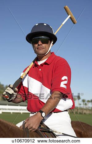 Stock Image - Polo Player holding polo stick on horseback on polo field. Fotosearch