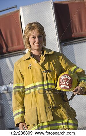 Stock Photo - Portrait of female firefighter holding helmet. Fotosearch