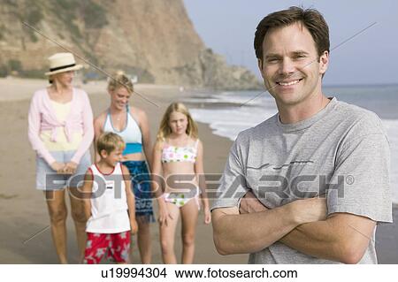 Picture - Portrait of man on beach with family. Fotosearch