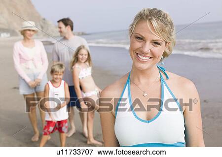 Stock Photo - Portrait of woman on beach with family. Fotosearch