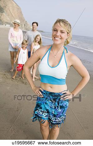 Stock Photo - Portrait of woman on beach with family. Fotosearch