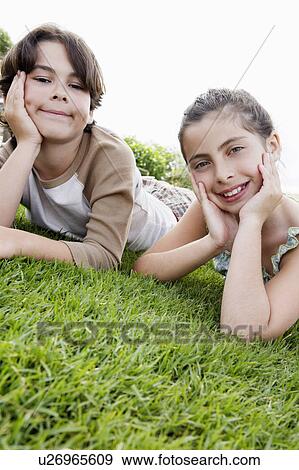 Pre-teen boy and girl reclining, hands on chin on grass View Large Photo Image Stock Photo - Pre-teen boy and girl reclining, hands on chin on grass. Fotosearch