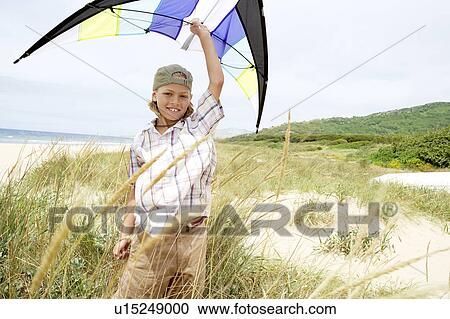 Pre-teen boy arms raised, holding kite above head on beach View Large Photo Image Stock Image - Pre-teen boy arms raised, holding kite above head on beach. Fotosearch