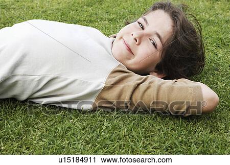 Pre-teen boy lying on back in grass, hands behind head, ground view View Large Photo Image Stock Image - Pre-teen boy lying on back in grass, hands behind head, ground view. Fotosearch