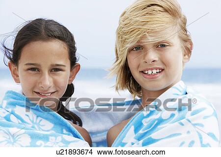 Picture - Pre-teen children wrapped in single towel on windy day. Fotosearch