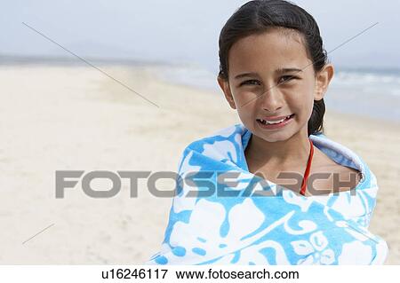 Stock Photo - Pre-teen girl Wrapped in a Towel, standing on beach. Fotosearch