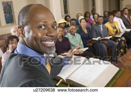 Stock Photo - Preacher at altar with Bible preaching to Congregation, portrait, close up. Fotosearch