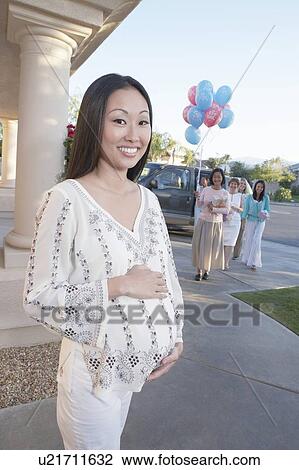 Stock Image - Pregnant Woman on Her Way to Her Baby Shower outside house. Fotosearch
