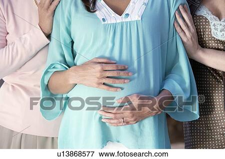 Stock Photo - Pregnant Woman with Friends, mid section. Fotosearch