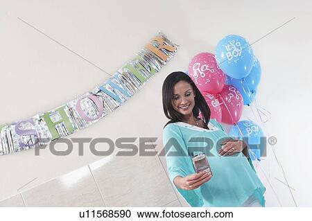 Stock Image - Pregnant Woman with Her New Baby Monitor at baby shower. Fotosearch