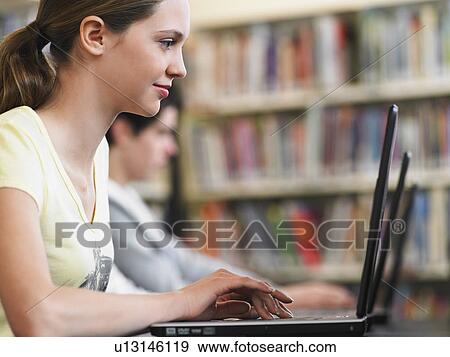 Profile view of teenaged girl studying laptop in school libray View Large Photo Image Stock Photo - Profile view of teenaged girl studying laptop in school libray. Fotosearch