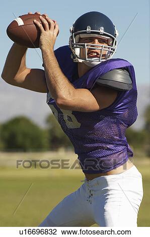 Stock Image - Quarterback throwing ball on field, portrait. Fotosearch
