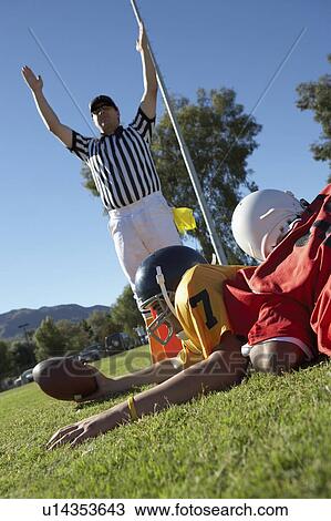 Stock Image - Referee signalling touchdown over football player tackled in end zone. Fotosearch