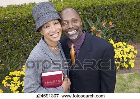 Stock Photo - Religious Couple with Bible in garden, portrait, high angle view. Fotosearch