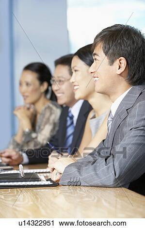 Row of business people sitting at table in conference room View Large Photo Image Stock Image - Row of business people sitting at table in conference room. Fotosearch