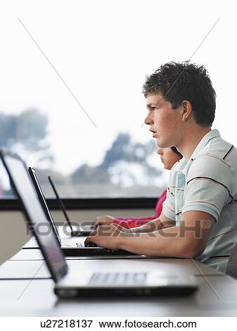 Stock Photo - Row of teenage students using laptops in classroom. Fotosearch