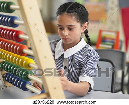 Stock Photo - Schoolgirl using abacus in classroom. Fotosearch