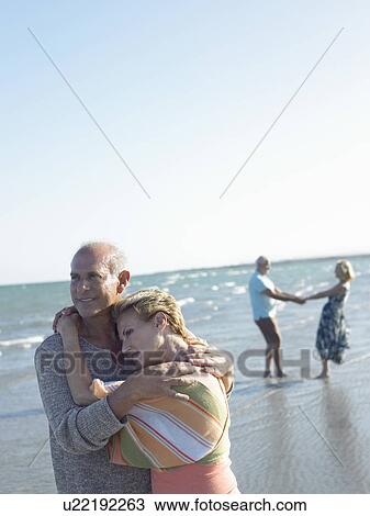 Stock Image - Senior couple embracing on beach. Fotosearch