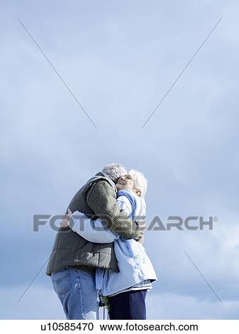 Senior couple embracing outdoors, (low angle view) View Large Photo Image Stock Image - Senior couple embracing outdoors, (low angle view). Fotosearch