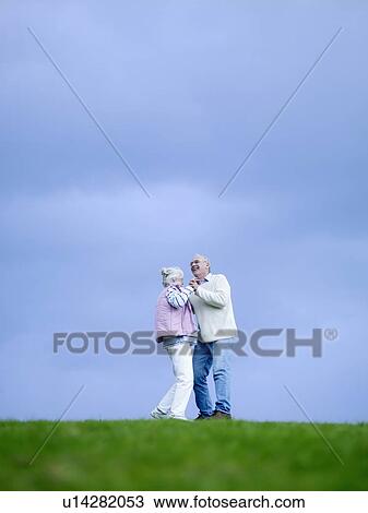Stock Image - Senior couple embracing outdoors, (low angle view). Fotosearch