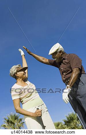 Senior couple giving high-five on golf course, (low angle view) View Large Photo Image Stock Photo - Senior couple giving high-five on golf course, (low angle view). Fotosearch