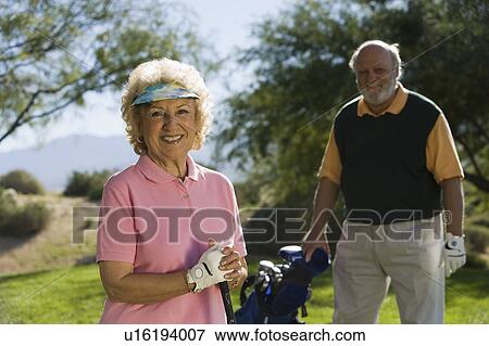 Senior couple in golf course, smiling, focus on woman, (portrait) View Large Photo Image Stock Photo - Senior couple in golf course, smiling, focus on woman, (portrait). Fotosearch