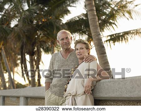 Senior couple leaning against wall, palm trees in background View Large Photo Image Stock Image - Senior couple leaning against wall, palm trees in background. Fotosearch