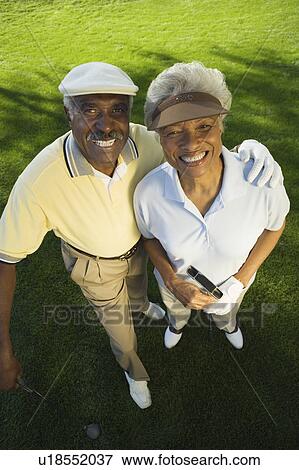 Stock Photo - Senior couple on golf course, smiling, (portrait), (elevated view). Fotosearch