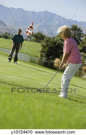 Stock Image - Senior couple playing golf. Fotosearch