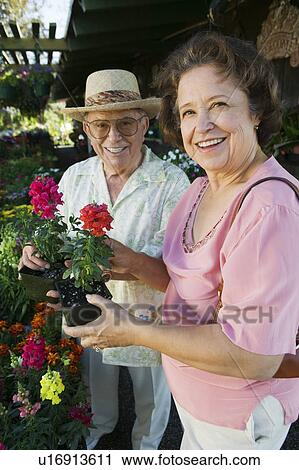 Stock Image - Senior Couple Shopping for flowers at plant nursery, portrait. Fotosearch
