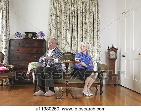 Senior couple sitting at opposite ends of sofa with arms crossed View Large Photo Image Stock Image - Senior couple sitting at opposite ends of sofa with arms crossed. Fotosearch