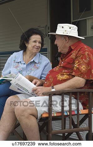 Stock Photo - Senior couple sitting beside caravan. Fotosearch