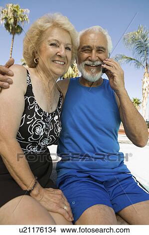 Senior Couple sitting outdoors, man using mobile phone, portrait. View Large Photo Image Picture - Senior Couple sitting outdoors, man using mobile phone, portrait.. Fotosearch